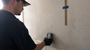 Technician using Protimeter capacitance scanner and thermal imaging camera for comprehensive moisture detection